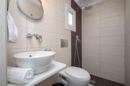 a bathroom with a sink and a toilet and a mirror at Saint George Hotel in Naxos Chora
