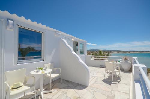 a white balcony with white chairs and tables and the ocean at Saint George Hotel in Naxos Chora