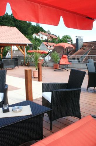 a patio with tables and chairs and a red umbrella at Gasthof und Pension Zur Frischen Quelle in Heigenbrücken