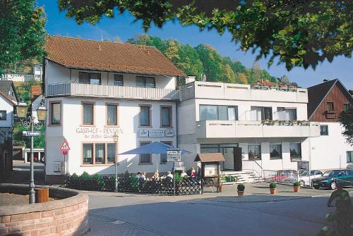 a white building with people sitting outside of it at Gasthof und Pension Zur Frischen Quelle in Heigenbrücken