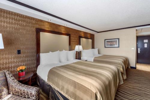 a hotel room with two beds and a chair at Best Western Plus Edmonton Airport Hotel in Leduc