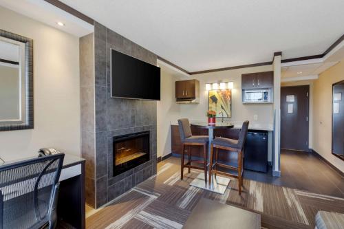 a living room with a fireplace and a dining room at Best Western Plus Edmonton Airport Hotel in Leduc