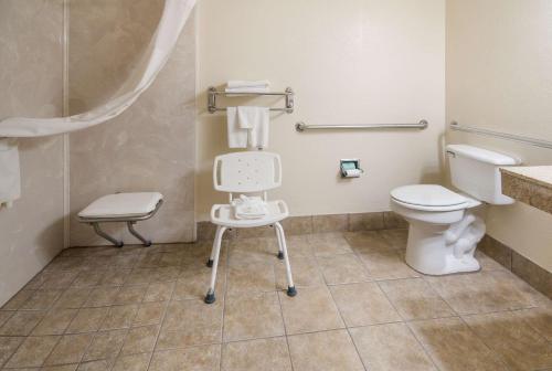 a bathroom with a toilet and a chair in it at Quality Inn & Suites Granbury in Granbury