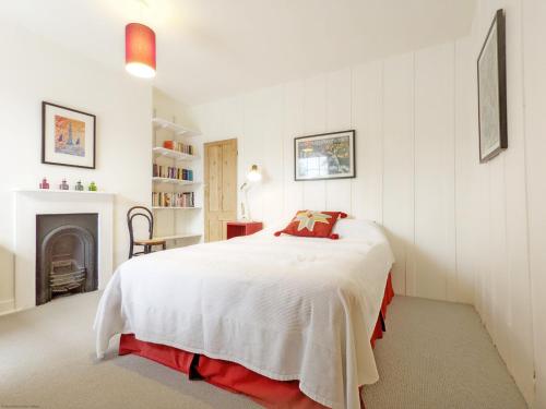 南海靈的住宿－Dolphin Cottage - Hayling Island，一间白色卧室,配有一张床和一个壁炉
