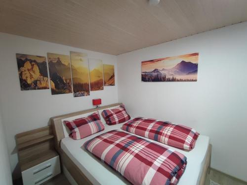 a bedroom with two beds and paintings on the wall at Ferienwohnung Nagelfluh Allgäu in Oberreute