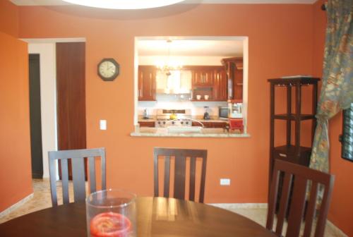 a dining room with orange walls and a table and chairs at E&J Boutique Residences in Sosúa