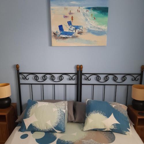 uma cama com duas almofadas e uma foto de uma praia em Villa julima em Playa Blanca