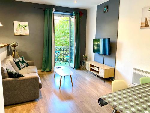 a living room with a couch and a table and a tv at Appartement au cœur de breil sur roya in Breil-sur-Roya