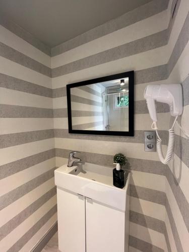 a bathroom with striped walls and a sink and a mirror at La Casa de Invitados in Zaragoza