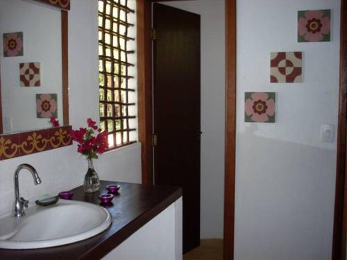 un baño con lavabo y un jarrón de flores en un mostrador en Casa Aldeia dos Pescadores - Agora com suíte e varanda no mezanino - PET Friendly, en Praia do Forte