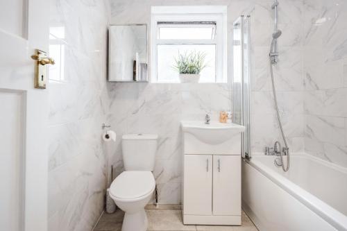 a white bathroom with a toilet and a sink at Lovely 4-BedRoom House Near Romford Station in Romford