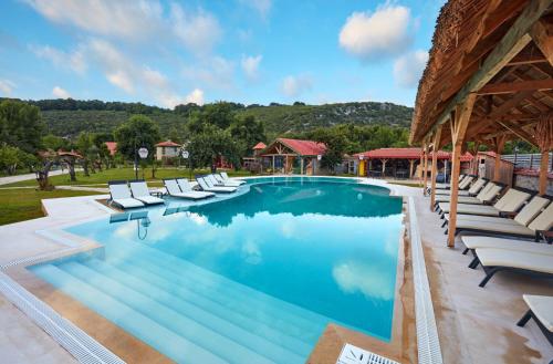 a swimming pool with lounge chairs next to a building at Dachas Cove Hotel in Agva