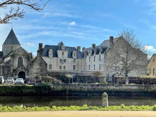 a large castle with cars parked in front of a river at Maison de Ville Lumineuse centre ville à pieds - Lit 160 in Quimper