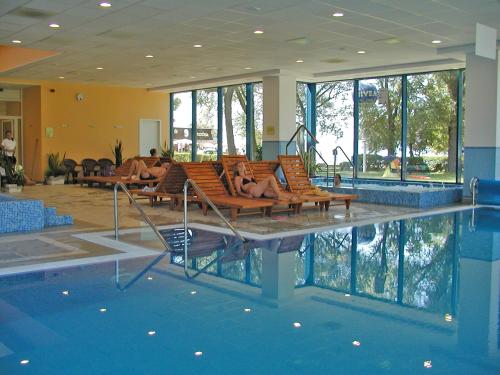 uma piscina com pessoas deitadas em cadeiras ao lado de uma piscina em Hotel Magistern Konferencia és WellnessHotel em Siófok