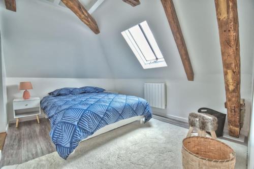 1 dormitorio con 1 cama con edredón azul y ventana en Superbe appartement centre-ville, en Nogent-le-Roi