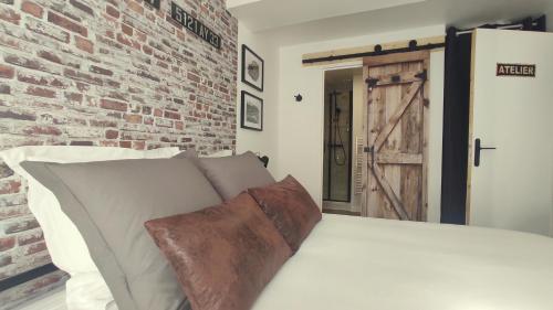 a bedroom with a white bed with a brick wall at Nouveau* Vintage Mecanic* Wifi*Netflix*Confort in Venette