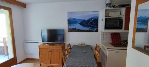 uma cozinha com uma televisão e uma mesa e cadeiras em Charmant appartement de 6 pers tout confort em Puy-Saint-Vincent