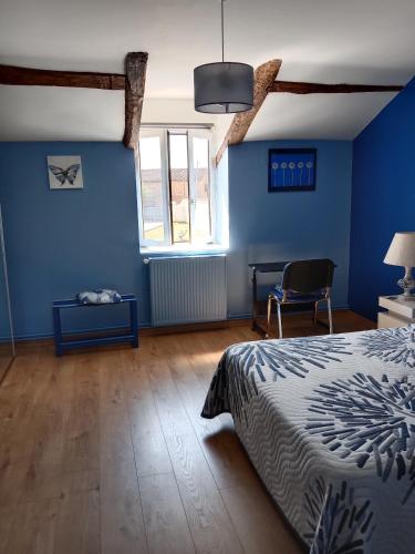a bedroom with blue walls and a bed and a chair at L OLIVIER DE ST LEGER in Château