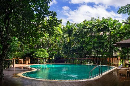 uma grande piscina num quintal com árvores em Ratchapruek Lanna Boutique em Chiang Mai