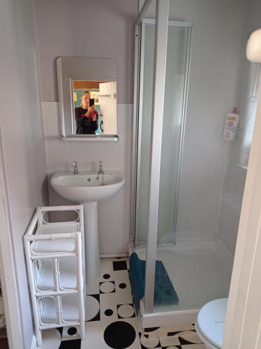 a woman taking a picture of a bathroom with a sink and shower at Maison atypique et charmante in Pleugueneuc