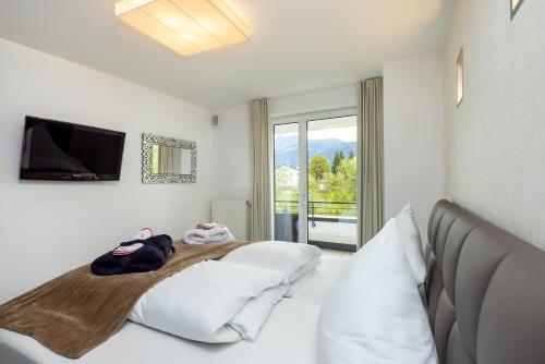 a white bedroom with a bed and a television at Enjoy ONE in Altenmarkt im Pongau