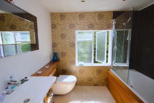 a bathroom with a toilet and a tub and a window at Kensington flat with roof terrace and sunshine in London