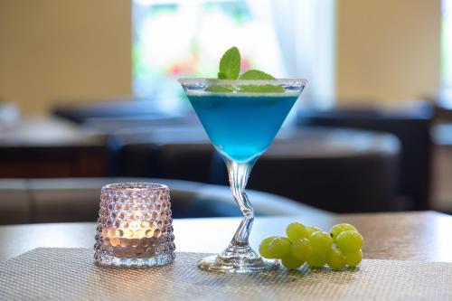 a blue drink in a glass sitting on a table with grapes at Bagińscy Spa in Pobierowo