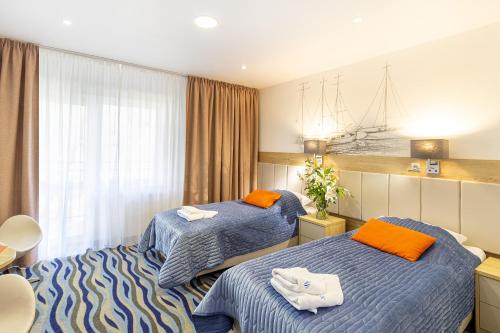 Habitación de hotel con 2 camas con sábanas de color naranja y azul en Bagińscy Spa, en Pobierowo