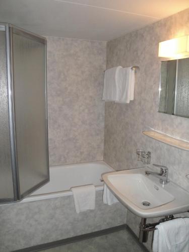 a bathroom with a shower and a sink and a tub at Landgasthof Grossteil in Giswil
