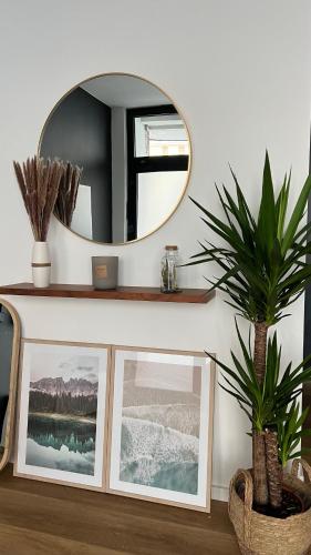 a mirror on a wall with a plant and a picture at Designwohnung Schaufenster sehr zentral gelegen in Hannover