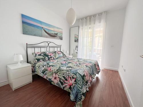 a bedroom with a bed with a floral bedspread at Apartamento Narváez- Altos Del Tomillar in Torre del Mar