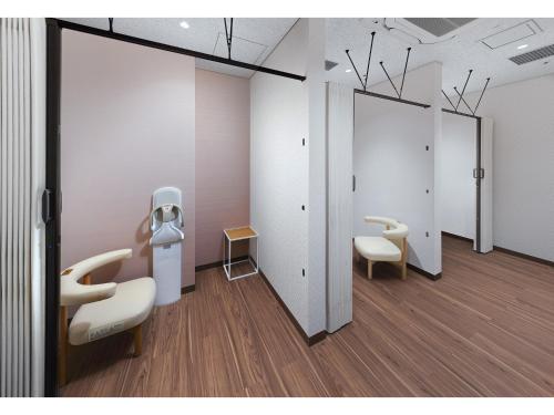 a room with white walls and two chairs and a mirror at Villa Fontaine Grand Haneda Airport in Tokyo