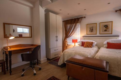 a bedroom with two beds and a desk in it at Cape Pillars Boutique Hotel in Durbanville