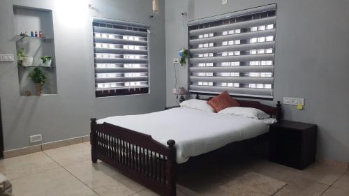 a bedroom with a bed with white sheets and two windows at Good vibes in Kallar Vattiyar