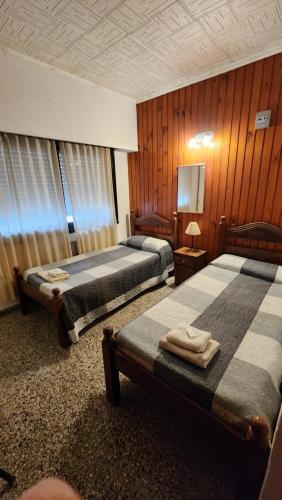 2 camas en una habitación con paneles de madera en Hotel Correa Playa en San Clemente del Tuyú