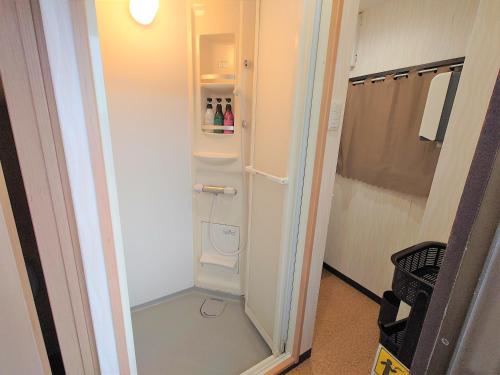 a small bathroom with a door open to a refrigerator at Stay Inn KOTO in Kyoto