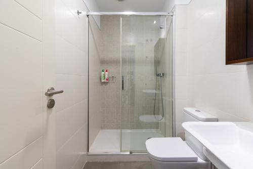 La salle de bains blanche est pourvue d'une douche et de toilettes. dans l'établissement Veoapartment Rastro, à Séville