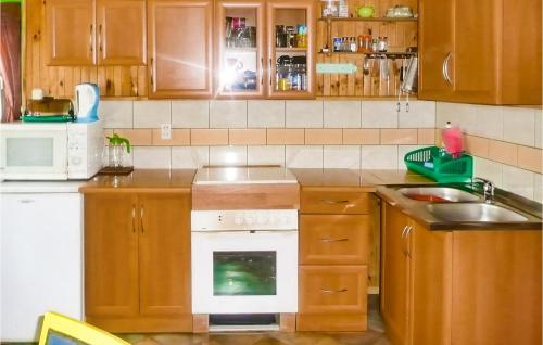La cuisine est équipée de placards en bois et d'une cuisinière blanche. dans l'établissement Nice Home In Ostrda With Kitchen, à Ostróda