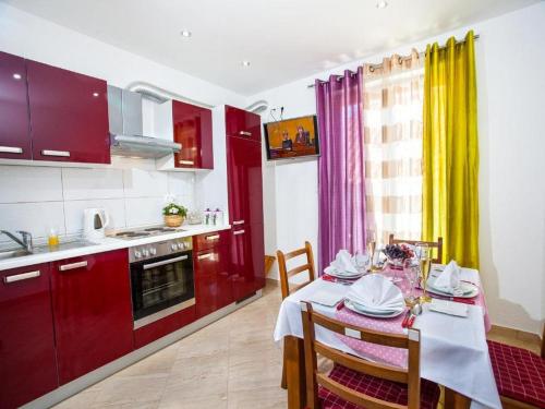 eine Küche mit roten Schränken und einem Tisch mit Stühlen in der Unterkunft Lux apartment Mare By the Sea & Beach in Baška Voda