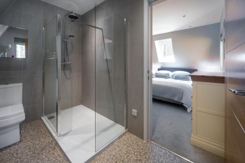 a bathroom with a shower with a toilet and a bed at Liz's Lodge by Big Skies Cottages in Weybourne