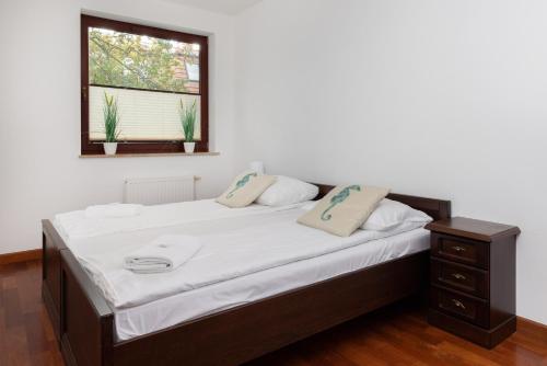 una camera da letto con un letto con lenzuola bianche e una finestra di Apartamenty Zatoka Górny Sopot a Sopot
