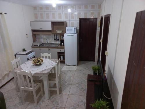 Il comprend une petite cuisine avec une table et un réfrigérateur blanc. dans l'établissement Casa inteira II - 2 quartos, à Pomerode