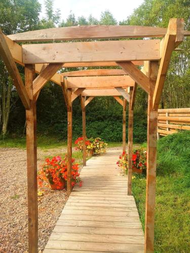 a wooden pergola with a wooden walkway with flowers at Beautiful Wooden tiny house, Glamping cabin with hot tub 2 in Tuxford