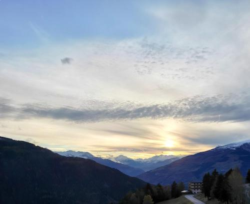 a cloudy sky with the sun setting over mountains at Maison de charme à Séez avec vue sur montagne, cheminée in Séez