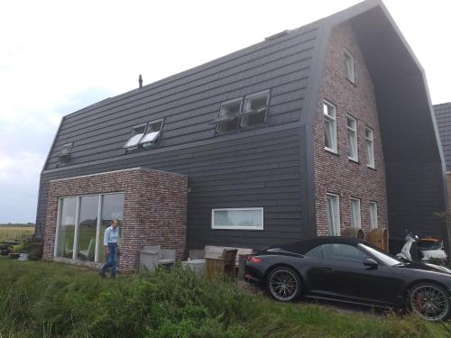 een zwarte auto geparkeerd voor een huis bij Oomes Huus - Sleep by Hästens, Wake with Coffee in Den Hoorn