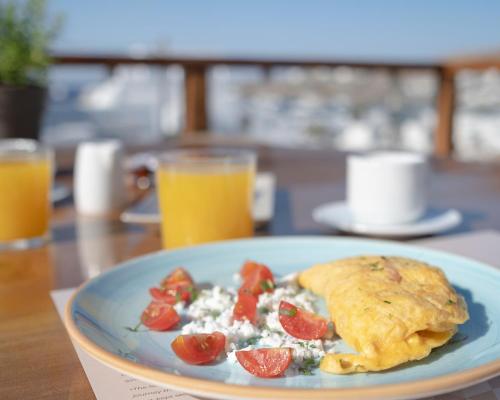 a plate of food with a omelet and tomatoes on a table at Mykonos Essence Adults Only in Ornos
