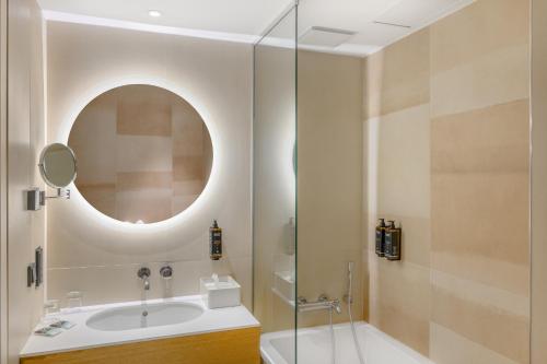 a bathroom with a tub and a sink and a mirror at Mercure Debrecen in Debrecen