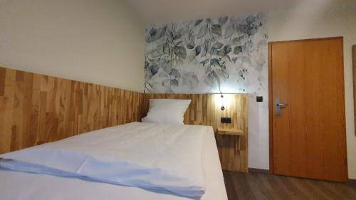 a bedroom with a white bed and a wooden wall at Der Höfener Garten in Nuremberg