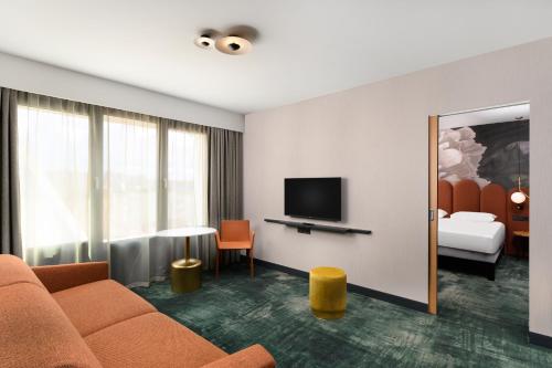 a hotel room with a couch and a television at Mercure Debrecen in Debrecen
