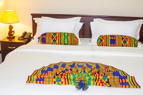 een bed met een kleurrijke deken en een telefoon bij Lou Ralph Hotel in Accra